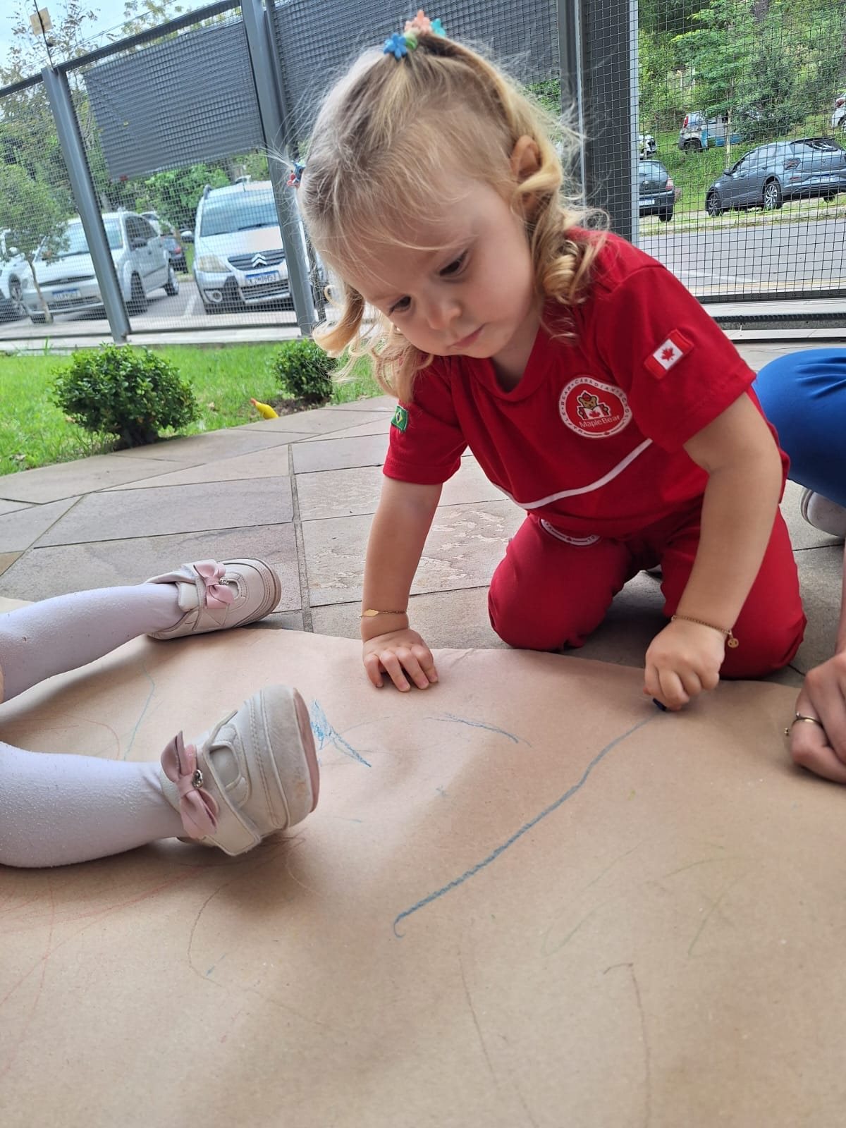 Criança do Nursery Maple Bear desenhando no chão